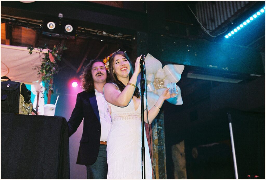 A bride speaks into a microphone on stage.
