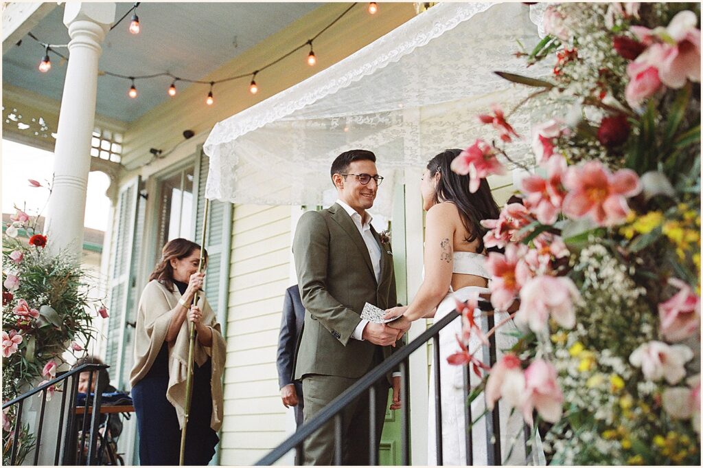 A groom smiles during a wedding ceremony on a New Orleans porch.
