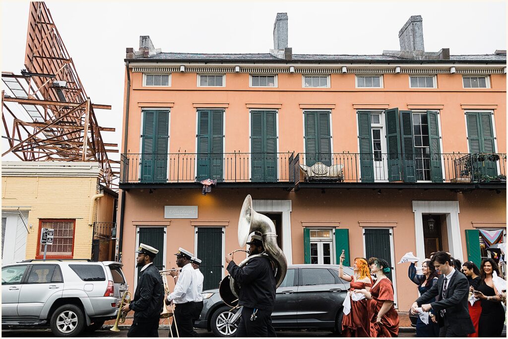 A brass band leads wedding guests down a French Quarter street.