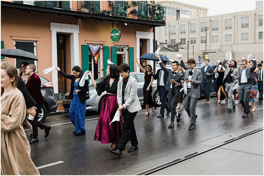 Wedding guests dance during a second line on a rainy day.