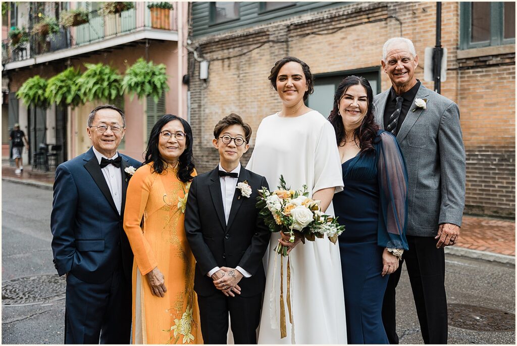 Two marriers pose for a portrait with their parents.