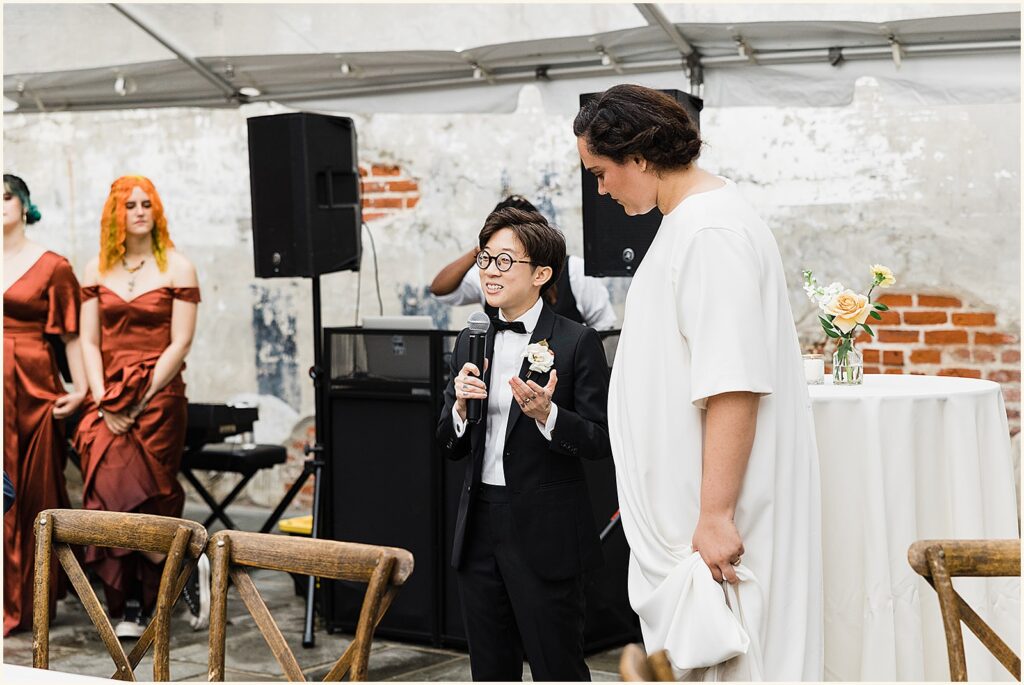 A marrier addresses wedding guests with a microphone.
