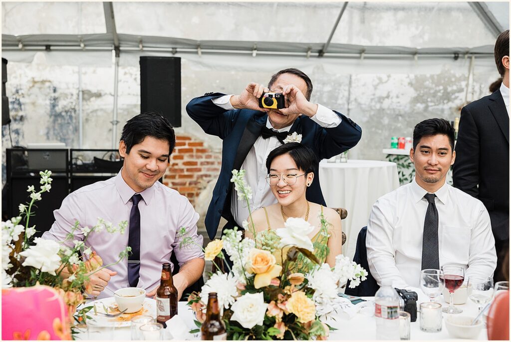 A wedding guest takes a photo with an instant camera at a rainy day wedding.