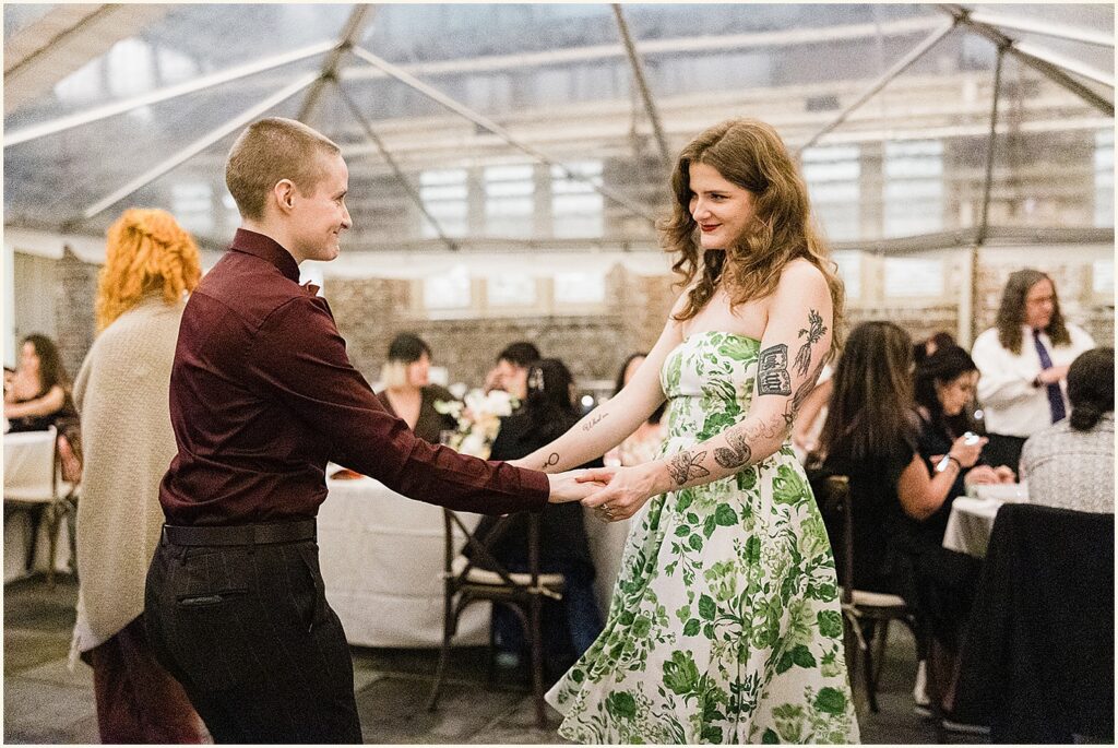 Two wedding guests smile as they step onto the dance floor.