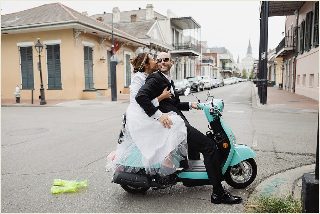 A bride kisses a groom's cheek on a moped at their New Orleans elopement.