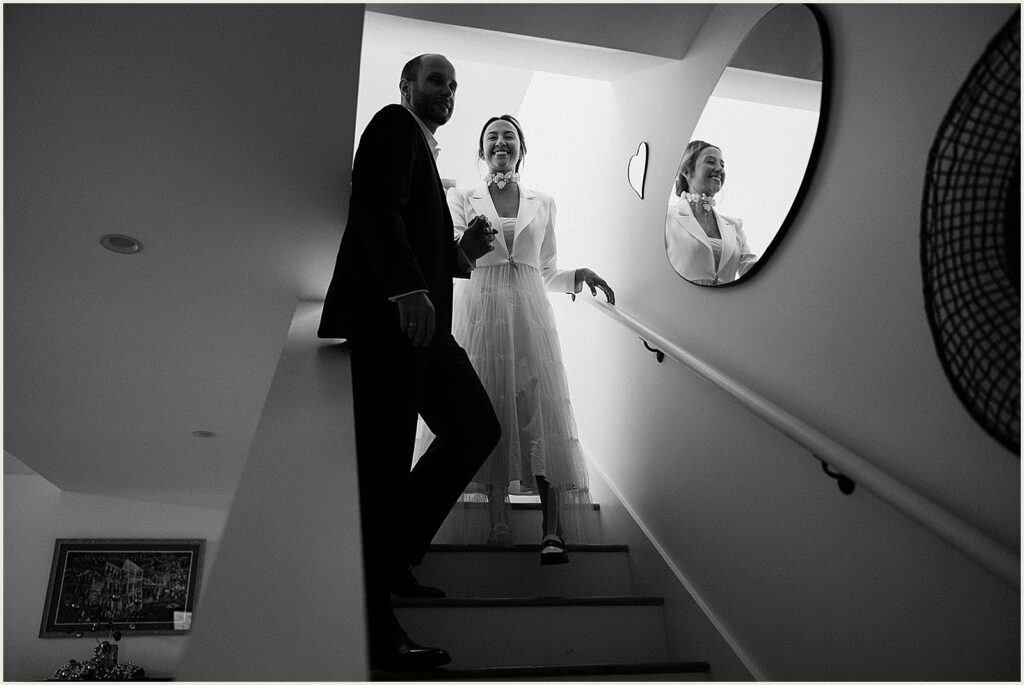 A bride and groom walk down the stairs at their New Orleans home.
