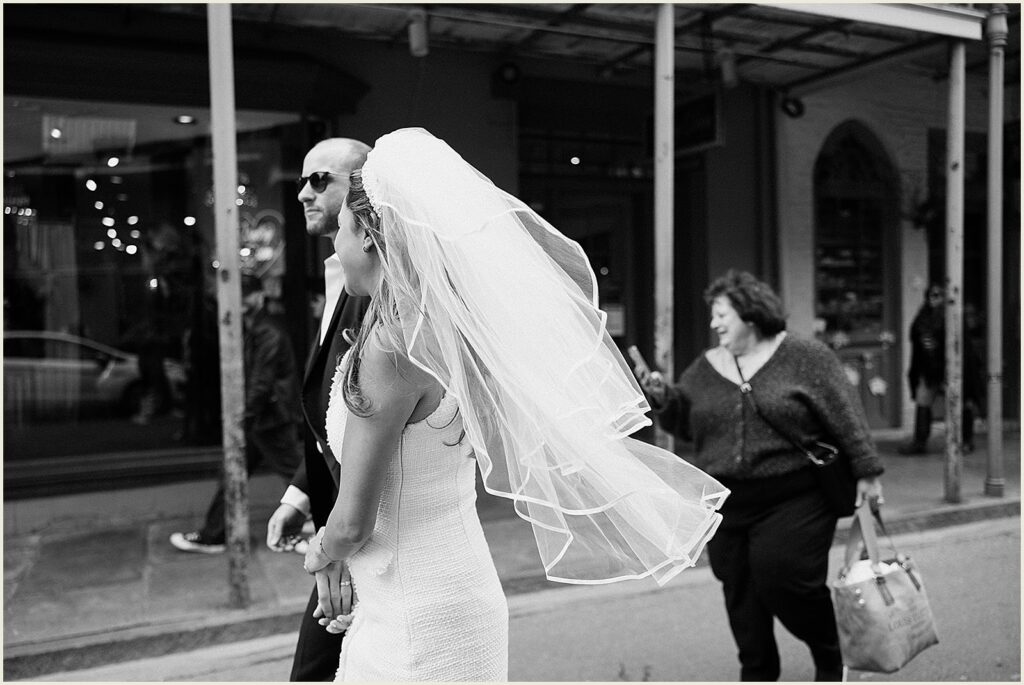 A New Orleans bride and groom cross a street with a family member.