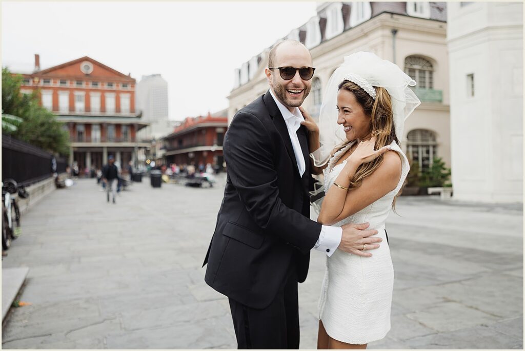A bride and groom laugh on the street outside Jackson Square.