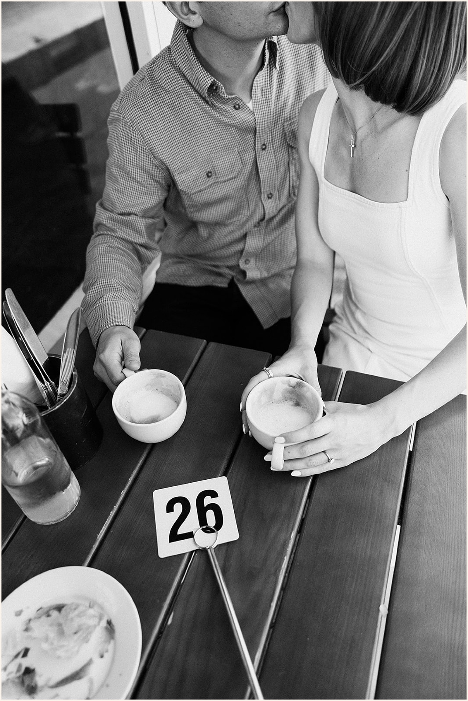 A man and woman kiss a a cafe table for Garden District photos.