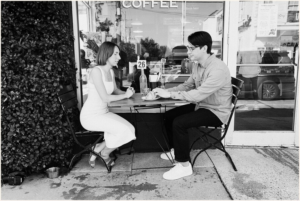 A man and woman sit on a sidewalk table at a Garden District cafe.
