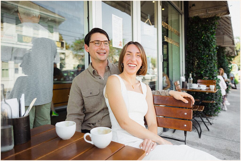 A man and woman laugh while they pose for a New Orleans engagement photos.