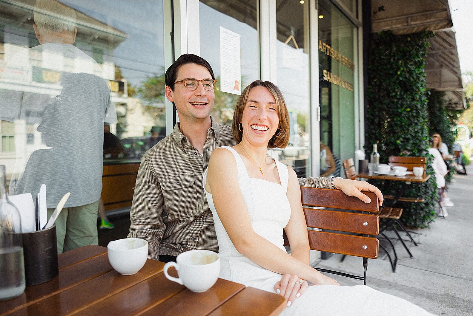 A man and woman laugh while they pose for a New Orleans engagement photos.