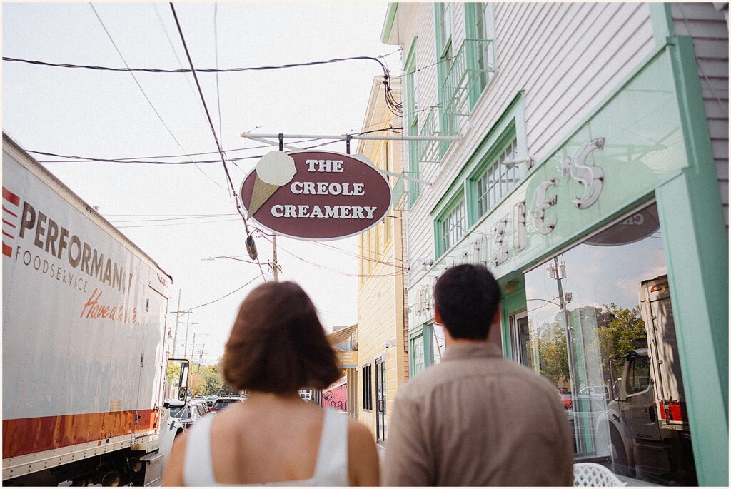 A man and woman walk towards a New Orleans ice cream shop.