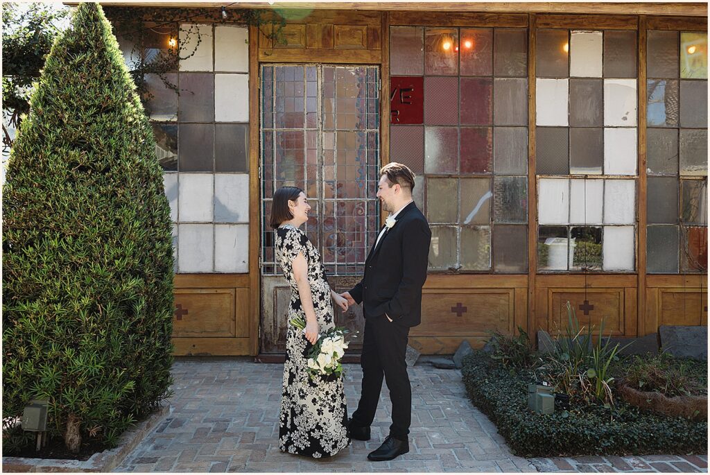 A bride and groom hold hands and smile at each other before their New Orleans elopement.