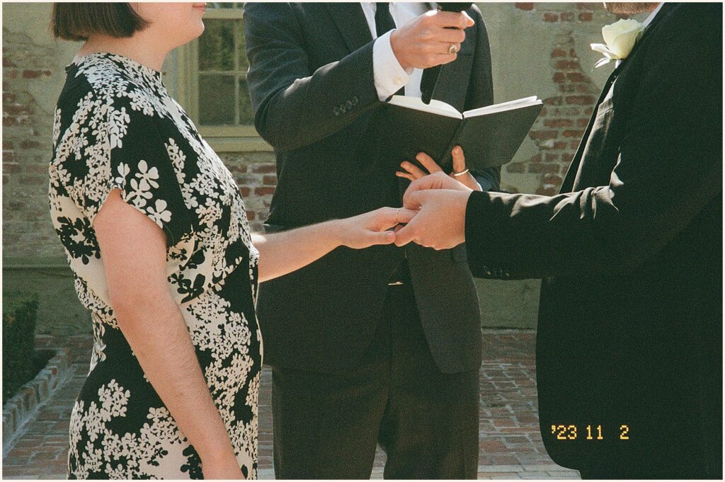 A groom puts a ring on a bride in a film photo.