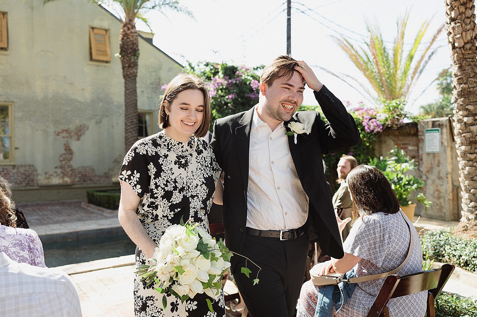 A bride and groom walk away from their ceremony smiling.