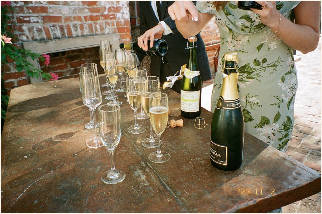 Wedding guests pour champagne into a glass.