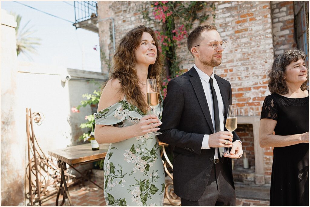 Smiling wedding guests hold champagne glasses.