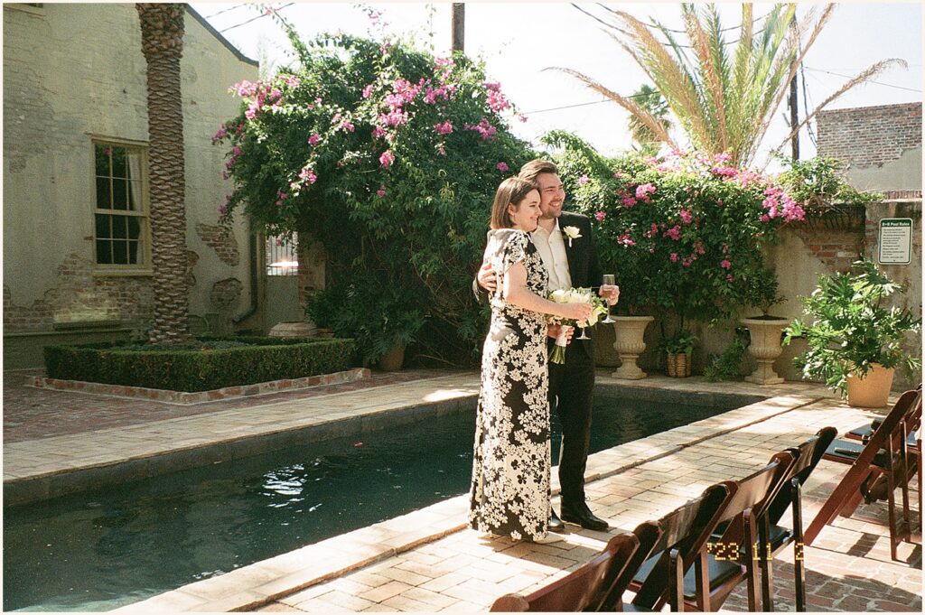 A bride and groom pose beside a reflecting pool at their New Orleans elopement at Race and Religious.