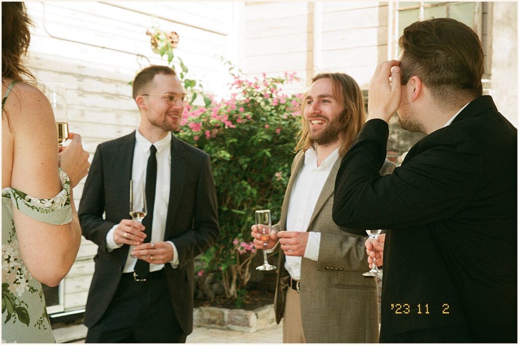 Wedding guests stand in a circle talking.