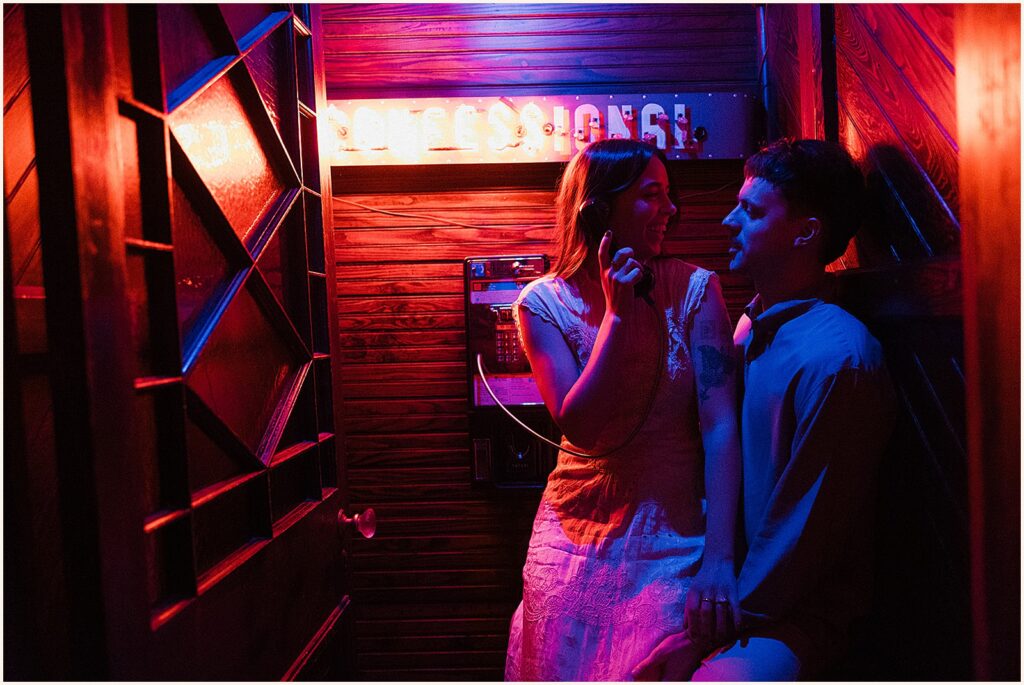 A woman sits on a man's lap in a vintage photo booth in New Orleans engagement photos.