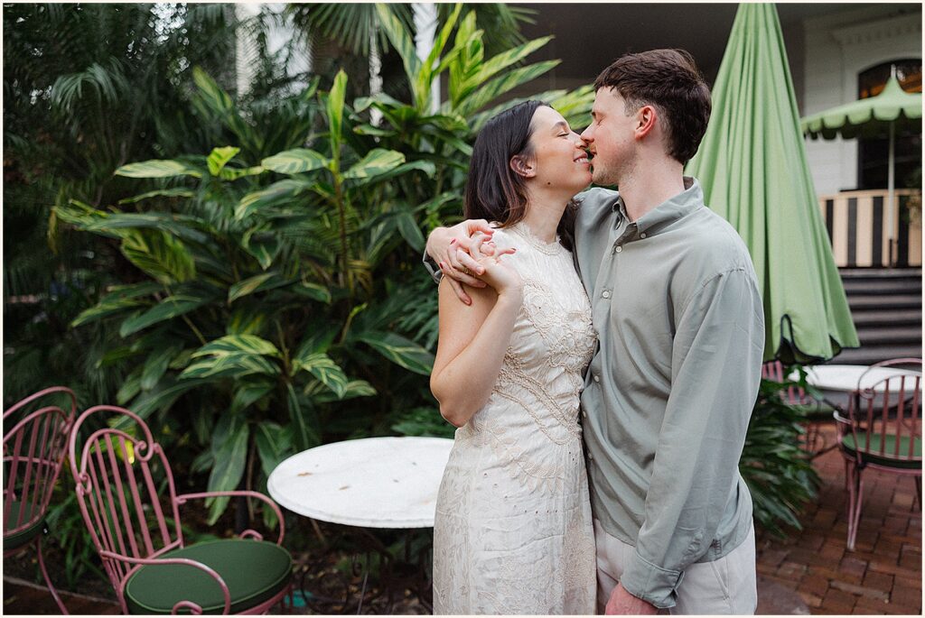 A man and woman lean towards each other for a kiss in a New Orleans courtyard.
